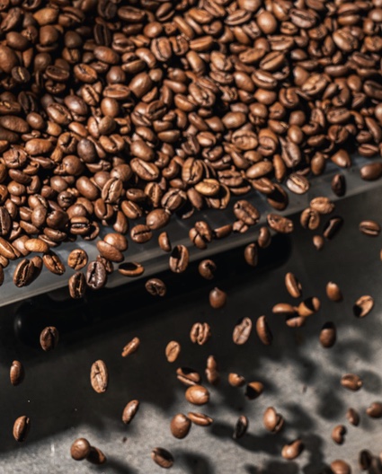 Roasted coffee beans falling onto a dark tray